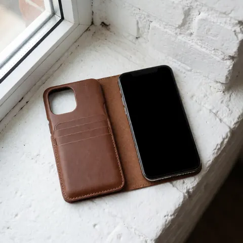 Vue rapprochée d'un étui en cuir marron posé sur une surface blanche, mettant en valeur la texture du matériau et le design minimaliste de l'accessoire.