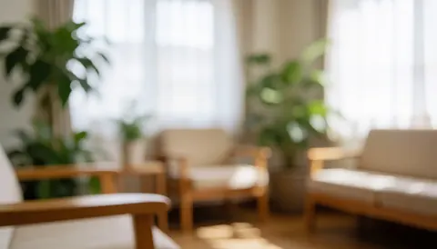 Intérieur apaisant avec lumière naturelle traversant une fenêtre, meubles en bois, plantes vertes et canapé blanc créant une ambiance de bien-être.