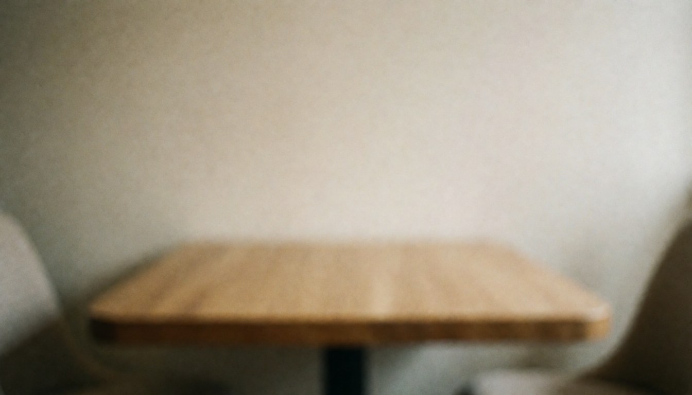 Table en bois avec mur beige en arrière-plan flou, créant une ambiance calme et professionnelle idéale pour ajouter du texte.