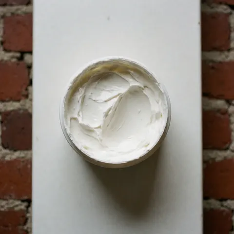 Vue de dessus de tubes de crème pour pieds ouverts posés sur un sol en briques rouges avec une texture douce et propre, idéal pour la réflexologie.
