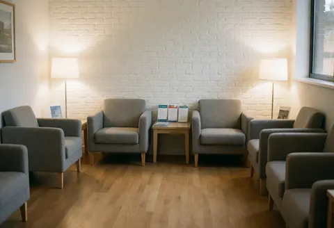 Vue d'une salle d'attente clinique lumineuse et ordonnée, équipée de chaises, de lampes et de brochures sur une table.