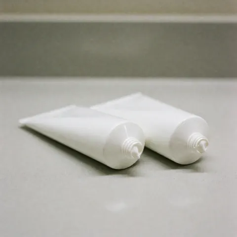 Plusieurs tubes de crème musculaire disposés proprement sur une surface blanche, éclairage doux et flou en arrière-plan pour un usage produit.