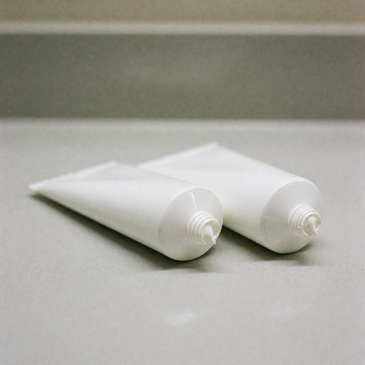 Plusieurs tubes de crème musculaire disposés proprement sur une surface blanche, éclairage doux et flou en arrière-plan pour un usage produit.