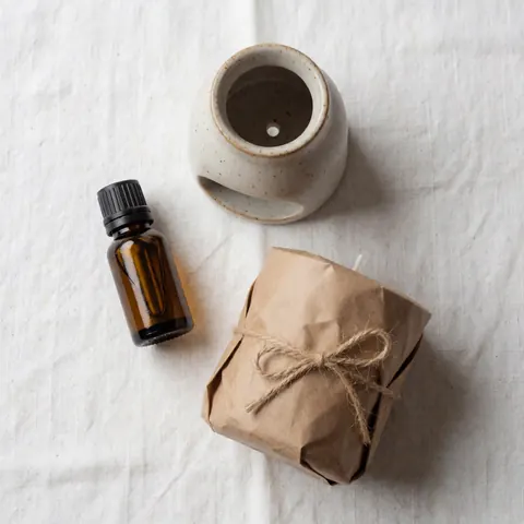 Vue de dessus d'un kit d'accueil minimaliste comprenant un diffuseur en céramique, une bougie en cire de soja et des éléments naturels sur fond clair.