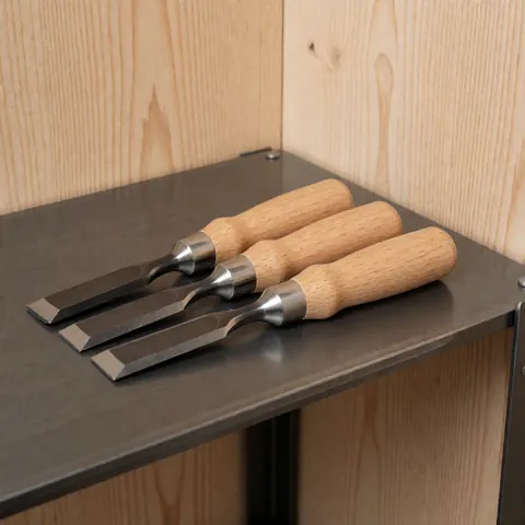 Trois ciseaux aux manches en bois clair et ferrules métalliques disposés sur une surface sombre, éclairage professionnel mettant en valeur le grain du bois et l'éclat du métal.
