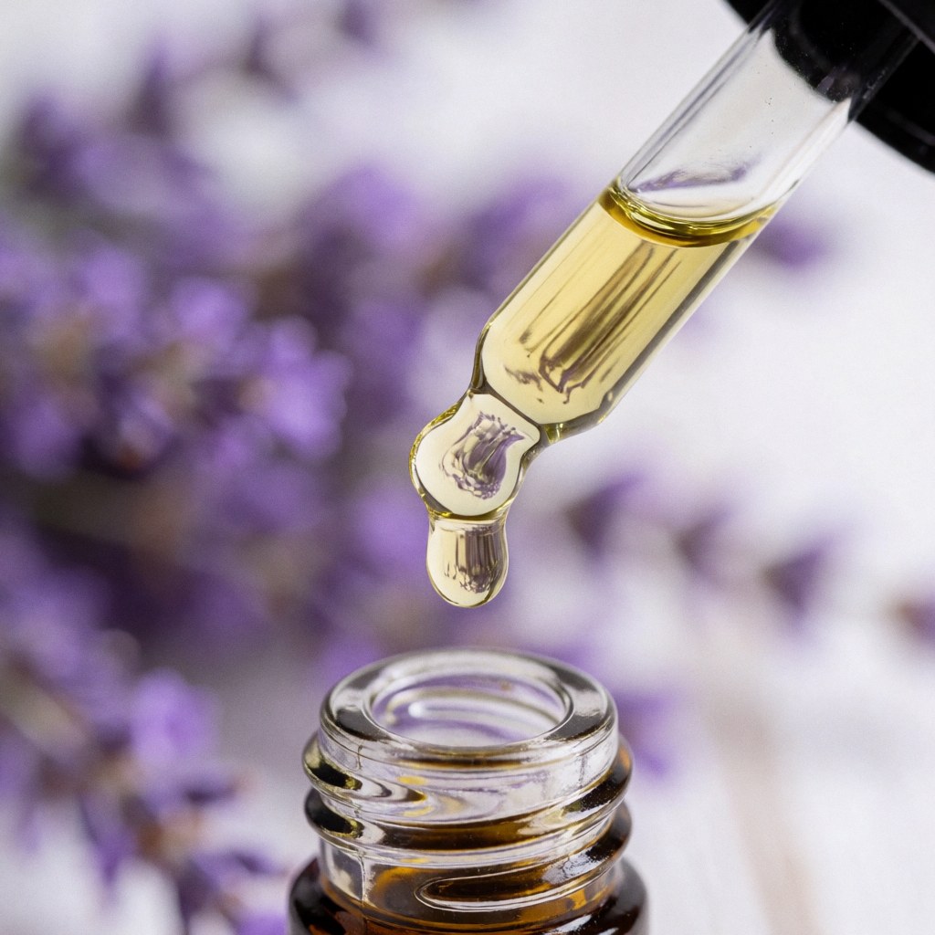 Gouttes d'huile essentielle de lavande tombant dans un flacon en verre sur fond de fleurs de lavande et toile blanche, éclairage naturel, produit de massage aux pierres chaudes.
