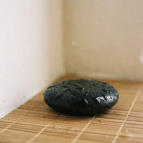 Gros plan sur une pierre chauffée utilisée pour un massage relaxant en spa, mettant en valeur sa texture lisse et naturelle.