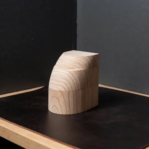 Gros plan d'un bloc de bois clair utilisé comme composant pour la fabrication de talons de chaussures, montrant le grain naturel du matériau.