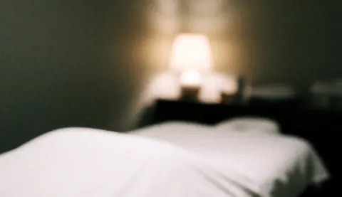 Lit blanc flou dans une pièce éclairée par une lumière chaude, idéal comme arrière-plan pour des textes sur les traitements d'acupuncture, évoquant tranquillité et professionnalisme.