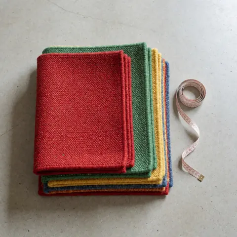 Vue de dessus d'une collection de tapis colorés disposés sur un sol en béton gris pour la présentation commerciale.