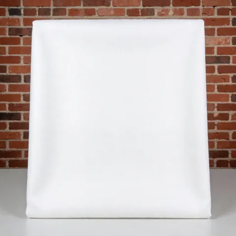 Gros plan d'un écheveau de fil de coton blanc pur posé sur une surface en briques rouges, évoquant le textile et la décoration intérieure moderne.