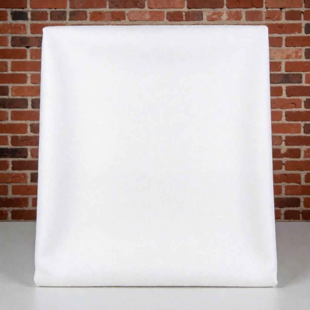 Gros plan d'un écheveau de fil de coton blanc pur posé sur une surface en briques rouges, évoquant le textile et la décoration intérieure moderne.