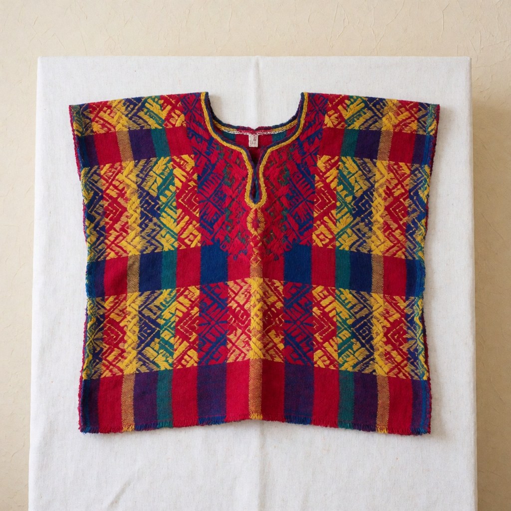 Huipil traditionnel guatémaltèque aux motifs géométriques colorés, présenté sur un fond blanc uni pour une utilisation commerciale.