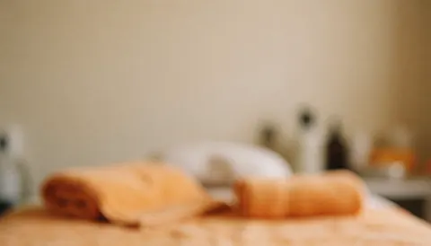 Arrière-plan de spa avec serviettes orange et bouteilles, tons chauds, idéal pour textes de massage et bien-être.