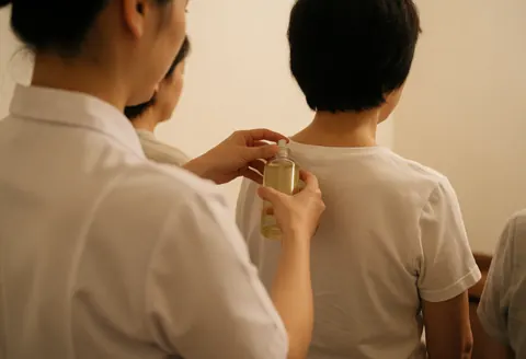 Un thérapeute en uniforme blanc applique de l'huile sur le dos d'un client dans un spa lumineux et apaisant.