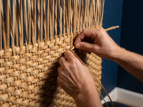Prise de vue rapprochée montrant les mains d'un artisan tissant des fibres naturelles de yuyo, mettant en évidence la texture et le savoir-faire traditionnel.
