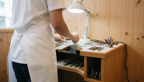 Vue d'un atelier de bijouterie organisé avec des outils disposés sur une table en bois, éclairage professionnel et préparation minutieuse pour la réparation.