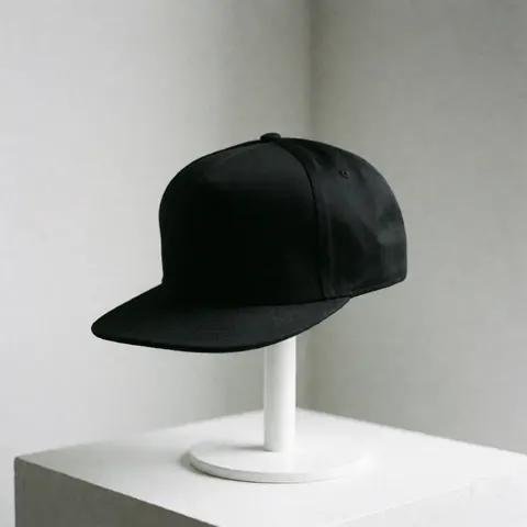 Casquette noire de style moderne posée sur un support blanc avec un fond gris clair et une lumière douce.