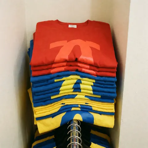 Plusieurs t-shirts colorés exposés sur un présentoir en métal, montrant des designs personnalisés pour la vente en magasin.