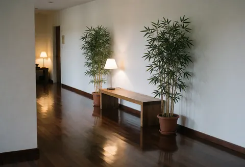 Couloir d'entrée de massage avec sol en bois poli, banc en bois, plantes de bambou et lampes, ambiance calme et accueillante.