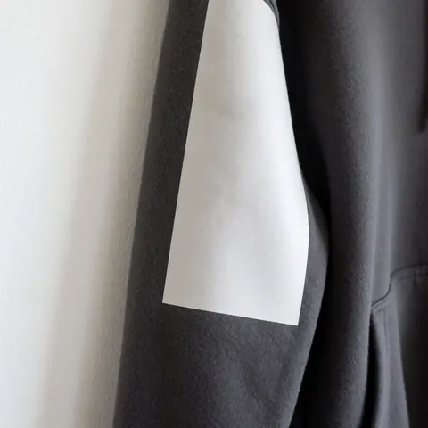 Photo de produit d'une veste en polaire grise à capuche présentant une texture mate douce, avec poches et fermeture éclair, sur fond blanc lumineux.