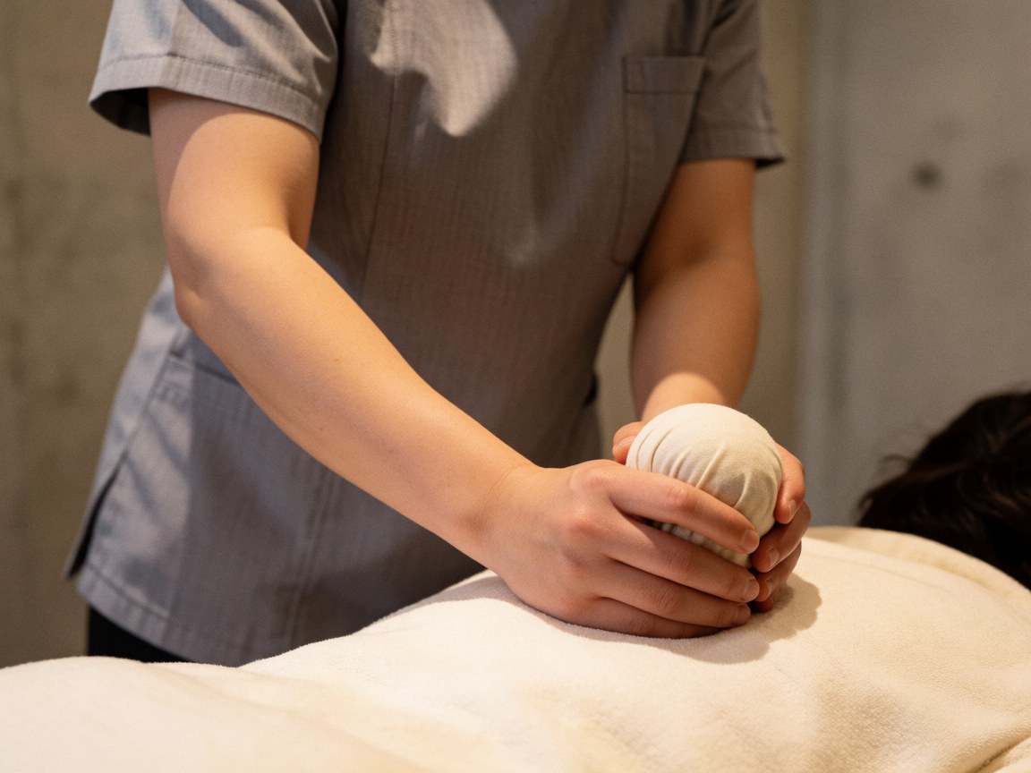 Un thérapeute professionnel applique une boule d'herbes chaudes sur le dos nu d'un client lors d'une séance de massage relaxant.