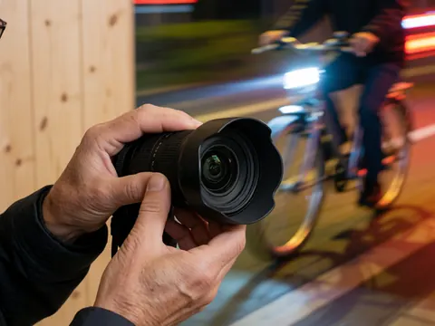 Photographe préparant soigneusement un objectif grand angle pour une prise de vue professionnelle, mettant en valeur le détail des mains et du matériel.