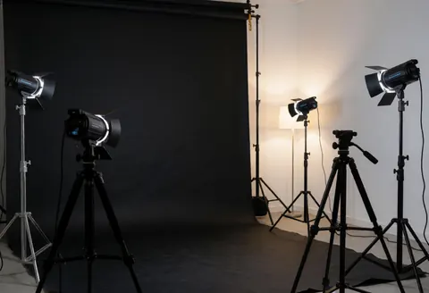 Un studio photographique professionnel avec un fond noir, des trépieds et du matériel d'éclairage prêts à l'emploi.