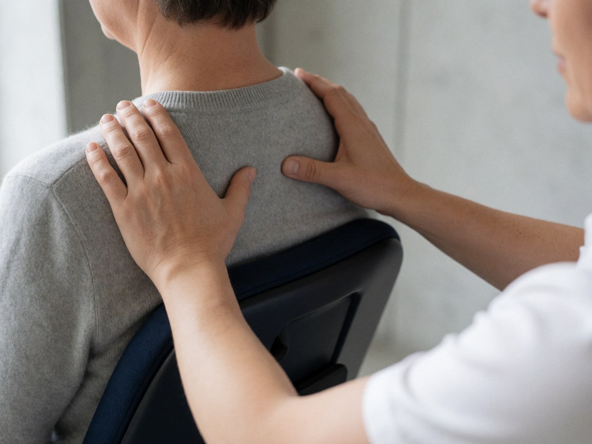 Prise de vue rapprochée montrant des mains effectuant une pression sur les points de l'épaule lors d'une séance de shiatsu.