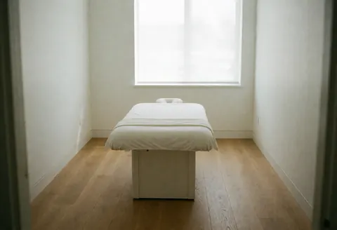 Salle moderne et propre avec lit blanc, sol en bois clair et fenêtre laissant entrer la lumière naturelle.