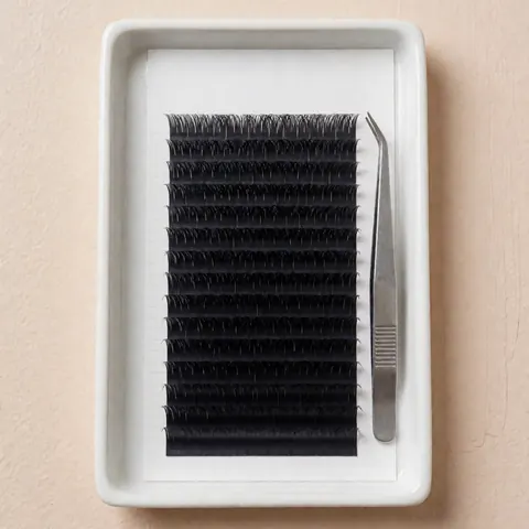 Des faux cils noirs disposés sur un plateau blanc accompagné de pinces à épiler, sur un fond beige clair pour une présentation de produit cosmétique professionnel.
