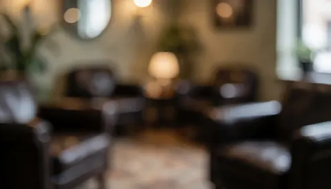 Arrière-plan flou d'un salon d'attente professionnel avec des fauteuils en cuir sombre, une lampe et des murs aux tons chauds.