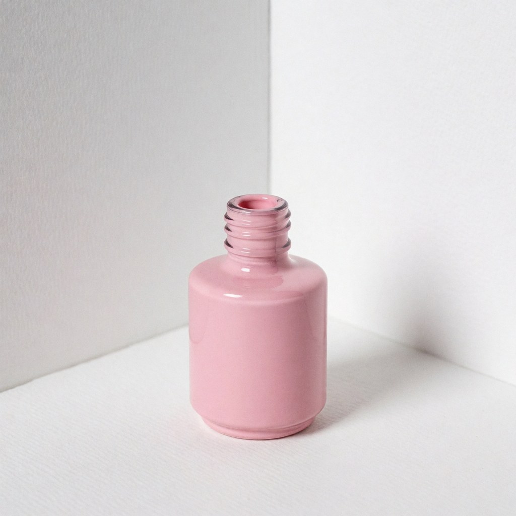 Flacon d'émail à ongles rose ouvert posé sur une surface blanche avec un fond uni, éclairage doux et professionnel pour catalogue de produits.