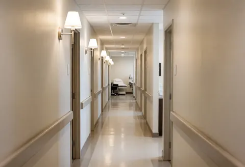 Couloir stérile et bien éclairé d'un centre de piercing, avec des lits de traitement au fond et des murs neutres, idéal pour les entreprises d'esthétique.