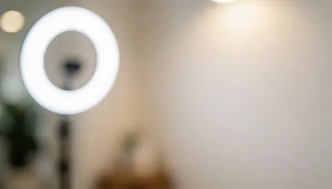 Arrière-plan flou avec lumière d'anneau blanche et mur neutre éclairé par une lumière chaude, adapté aux services de beauté.