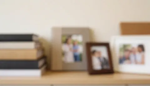 Arrière-plan doux et flou montrant des albums et des cadres photo disposés sur une étagère, idéal pour ajouter du texte concernant les services de photographie de graduation.