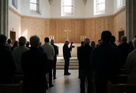 Photographe professionnel capturant un mariage dans une église avec autel, bougies et lumière naturelle. Scène montrant le service en action.