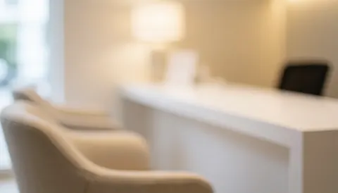 Arrière-plan flou d'une réception clinique avec des chaises confortables et un comptoir blanc, éclairage chaleureux et ambiance sereine pour textes.