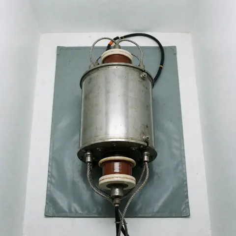 Magnétron pour micro-ondes avec isolants en céramique et câbles posés sur un tapis gris antistatique, fond blanc et éclairage clinique.