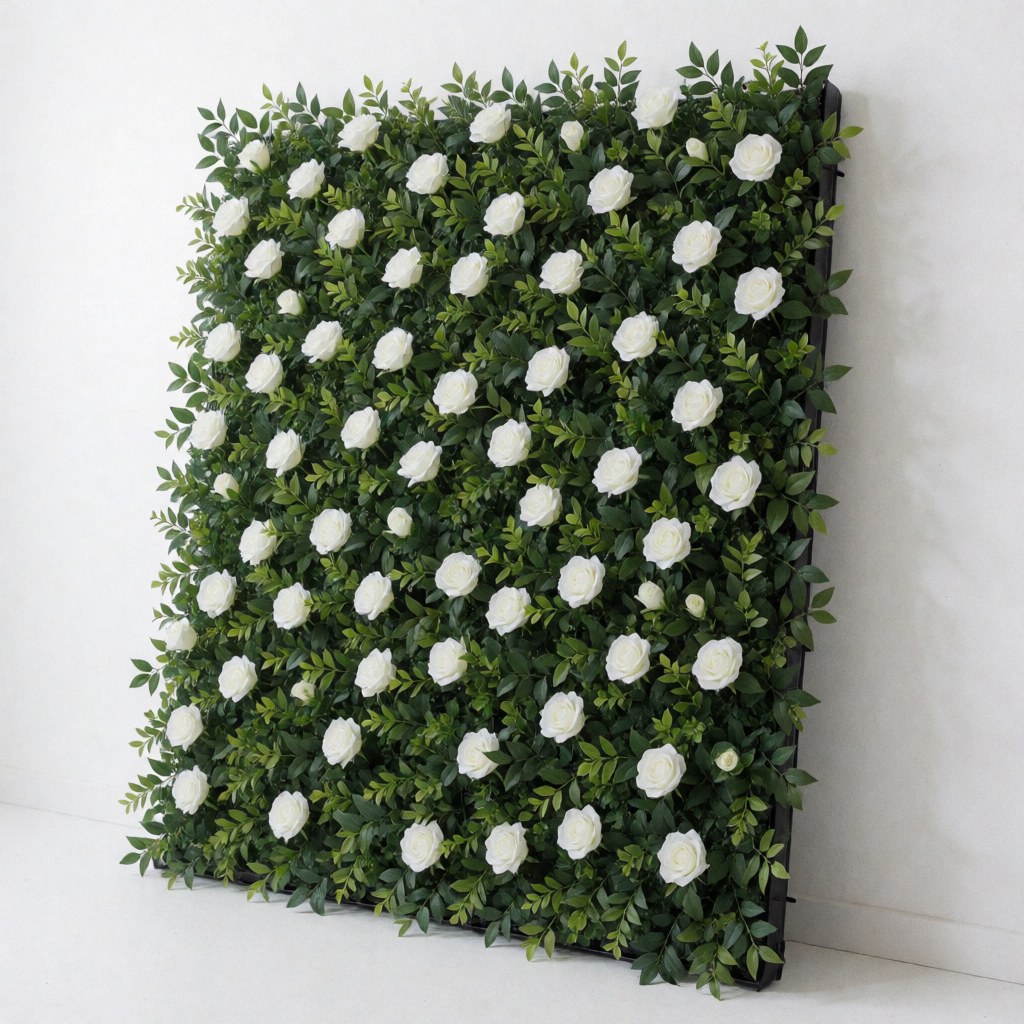 Panneau décoratif modulaire pour événements composé de roses blanches et de feuillage vert, idéal pour les fonds et la décoration, fixé sur un mur blanc, vu en angle.