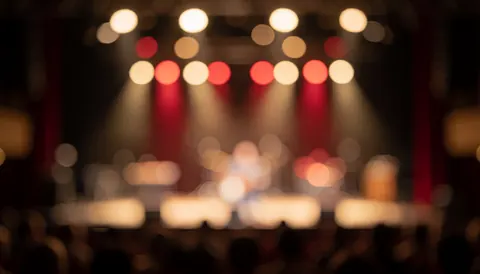 Fond de concert avec des lumières de scène en bokeh, des tons chauds et rouges, idéal pour les textes, sans personnes visibles.