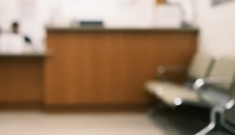 Arrière-plan professionnel de réception avec un comptoir en bois et des chaises d'attente, éclairage doux, idéal pour les textes et le design web.