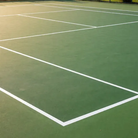 Court de tennis extérieur fraîchement peint avec surface verte et lignes blanches nettes sous lumière solaire, idéal pour illustrer des services d'installation.