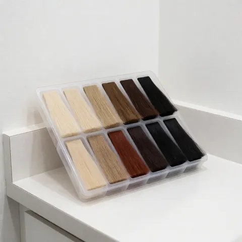 Plateau contenant des échantillons de cheveux synthétiques allant du platine au noir, posé sur un comptoir blanc dans un salon de coiffure.