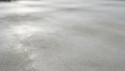 Fond de béton gris avec texture douce et lumière naturelle, idéal pour les textes des installateurs de courts de tennis.