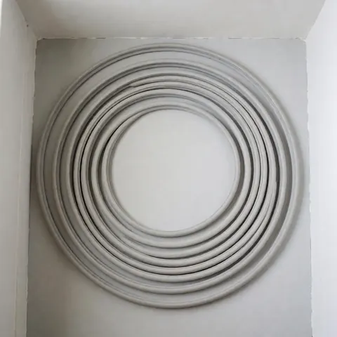 Joint d'étanchéité en spirale sur fond uni, idéal pour la réparation de réfrigérateurs. Texture uniforme et bords nets, éclairage neutre, parfait pour montrer un produit neuf prêt à l'installation.