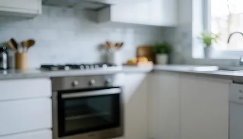 Arrière-plan de cuisine moderne avec four en acier inoxydable, plan de travail blanc et lumière naturelle, idéal pour textes sur les services de réparation de fours.
