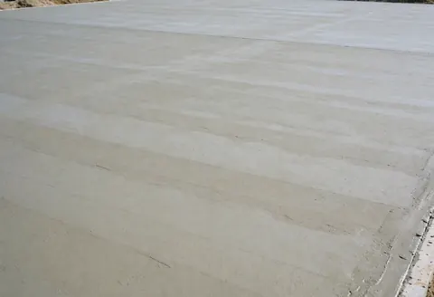 Surface de béton gris lisse et uniforme récemment coulée, servant de fond neutre idéal pour la publicité et les textes promotionnels des installateurs de courts.