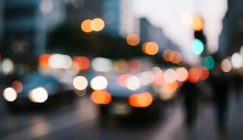 Fond abstrait de rue avec des lumières de voitures et de lampadaires floues en tons chauds et froids, idéal pour superposer du texte commercial.