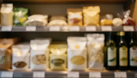 Fond d'étagère avec sacs de farine, bouteilles d'huile d'olive et autres ingrédients de cuisine, éclairage chaleureux et flou, idéal pour textes.